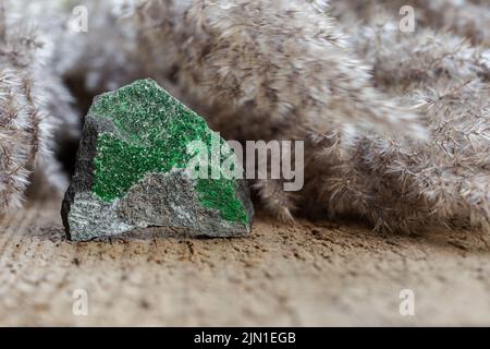 Pierre brute avec cristaux d'uvarovite sur fond de bois naturel. Groupe de grenat à roulement chromé. Gros plan sur les échantillons minéraux. Collection géologique Banque D'Images