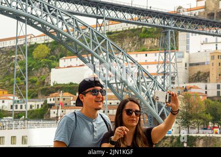 Couple prenant des selfies près du pont Luiz 1 pont au-dessus du fleuve Douro Porto Portugal qui a été conçu par Theophile Seyrig un partenaire de Gustave Eiffel Banque D'Images