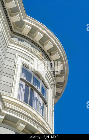 Mur de fenêtres incurvé d'un bâtiment de style victorien à San Francisco, Californie. Vue à angle bas d'un bâtiment avec mur recouvert de béton gris et décorati Banque D'Images