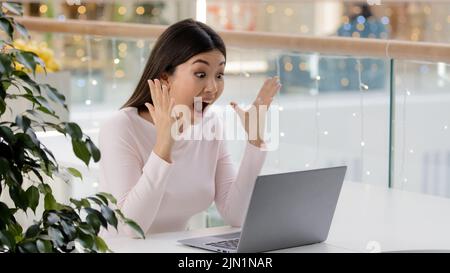 Femme asiatique coréenne heureuse avec ordinateur portable excitée surprise hurlant crier a obtenu la bourse d'université gagner en ligne la victoire aux enchères l'émotion gagnante femelle Banque D'Images