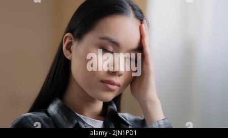 Mauvais sentiment asiatique fille millénaire femme difficile pensées penser résout problème frotte front avec la main se sent mal de tête souffre de migraine Banque D'Images
