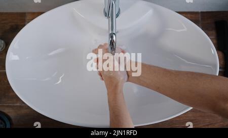 Gros plan hommes mains se laver dans un grand lavabo blanc à la maison dans la salle de bains dans l'hôtel hygiène quotidienne soins du corps homme laver les mains laver les paumes nettoie Banque D'Images