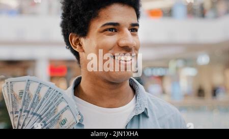 Motivé heureux inspiré afro-américain Guy banque client riche homme tenant fan de dollars des billets satisfaits de l'argent pense à la tâche de finances Banque D'Images
