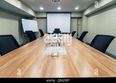 Salle de conférence pour les réunions d'affaires une grande table au milieu de la salle autour de chaises confortables, il y a de l'eau sur la table Banque D'Images