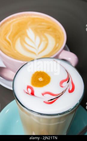 Verre de latte macchiato et une tasse de cappuccino avec de la mousse décorée Banque D'Images