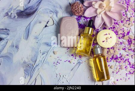 Belle composition de jaune cosmétique liquide visage corps essentiel bouteilles d'huile, sel de mer, barres de savon, fleur de lotus sur la surface des coups de pinceau plally. SP Banque D'Images