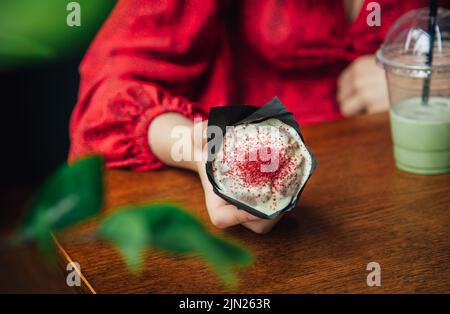 Latte au matcha glacé et gros gâteau dans un café entre les mains des femmes. Banque D'Images