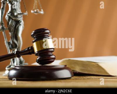 Un gaval en bois d'un juge, un livre ouvert et une figurine de bronze de Themis sur fond beige. Symboles d'un procès équitable et honnête. Constitution, Bible, Banque D'Images
