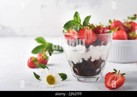 Carabines. Brownies, fraisiers frais et crème mascarpone sérés en couches sur verre sur fond blanc. Desserts en portions. Pas de cheesecak au brownie cuit Banque D'Images