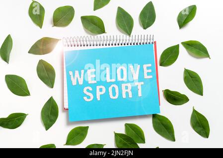 Affiche « We Love Sport ». Photo conceptuelle à aimer beaucoup de sport pratiquant des activités sportives travailler dehors Spiral Livre et papier blanc avec frais Banque D'Images