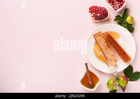 Roch Hachana. Pot de miel, nid d'abeille, pomme et grenade sur fond rose simple. Carte de vœux juive pour le nouvel an. Rosh Hashanah Holiday att Banque D'Images