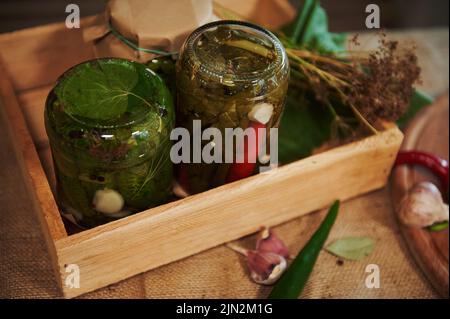 Encore la vie. Bocaux de piments marinés et de concombres marinés, à l'envers sur une planche de bois. Mise en conserve. Décapage. Banque D'Images