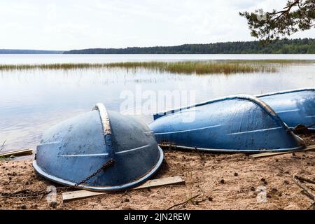 Des barques bleues se sont couché sur des talons sur une plage de sable, paysage côtier de lac Banque D'Images