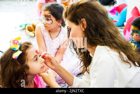 BAKOU,AZERBAÏDJAN- 13 MAI 2019 : la fille dessine le maquillage aquatique de petite fille. Peinture de visage. Loisirs pour les enfants. Banque D'Images