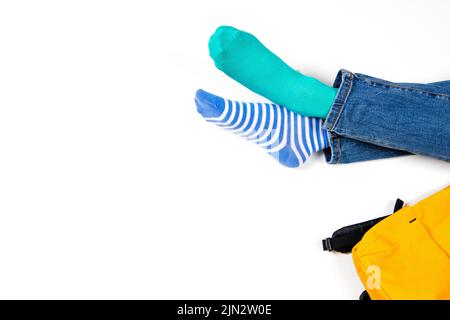 Enfant portant différentes paires de chaussettes. Les enfants se bas dans des chaussettes mal assorties, assis sur fond blanc. Journée des chaussettes impaires, semaine anti-intimidation, syndrome de Down Banque D'Images