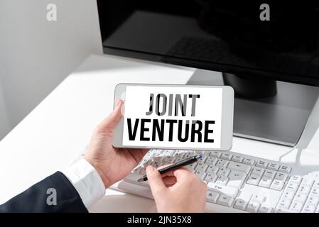 Affiche présentant joint Venture. Mot écrit sur l'arrangement de collaboration Parties Partenariat équipe Businesswoman tenant le téléphone mobile avec important Banque D'Images