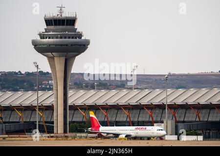 Un avion Iberia vu sur la piste de l'aéroport Adolfo Suarez Madrid Barajas passant par la tour de contrôle de la circulation aérienne. Banque D'Images