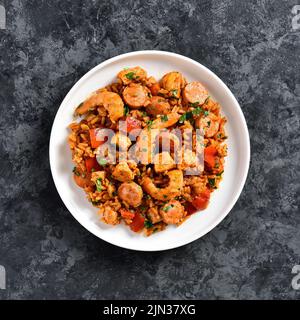 Jambalaya créole avec saucisses fumées, viande de poulet et légumes sur plaque sur fond de pierre bleue. Vue de dessus, plan d'appartement Banque D'Images