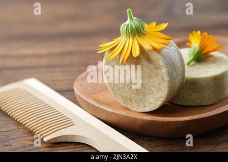 Morceaux naturels de shampooing calendula organique solide, fleur de calendula et peigne à cheveux en bois. Mise au point sélective. Banque D'Images