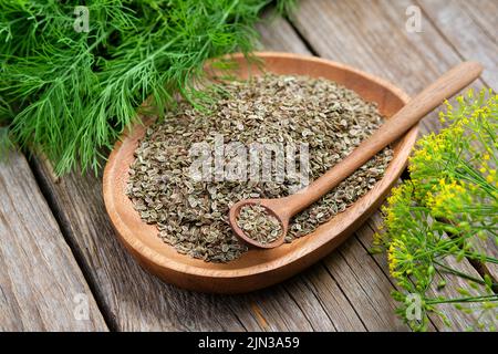 Assiette en bois de graines de fenouil et petits pains d'aneth vert frais sur panneau en bois. Banque D'Images