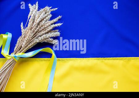 Bouquet d'oreilles de blé doré attaché avec un ruban jaune et bleu sur le fond du drapeau de l'Ukraine. Jour de l'indépendance de l'Ukraine, jour de la Constitution, FLA Banque D'Images