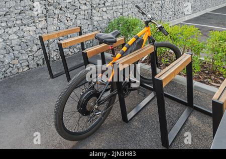 Vélo tout-terrain électrique garé dans un porte-vélos public à côté de la clôture en granit Banque D'Images