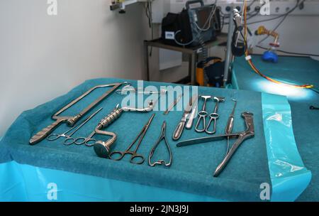 Jeu d'outils chirurgicaux en acier sur tissu bleu - instruments réels utilisés dans la tente médicale mobile, arrière-plan flou de la table d'opération Banque D'Images