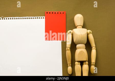 Poupée en bois et un morceau de papier vierge. Mannequin en bois avec feuilles de papier concept, espace vide. Créativité et art Banque D'Images