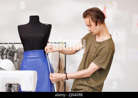 Portrait d'un jeune couturier sur le fond d'un mannequin et d'une machine à coudre Banque D'Images