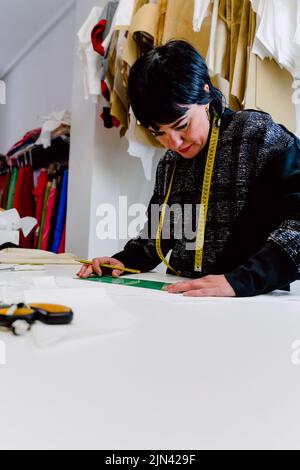 Couturière femme mesurant les vêtements pour les concevoir. Banque D'Images