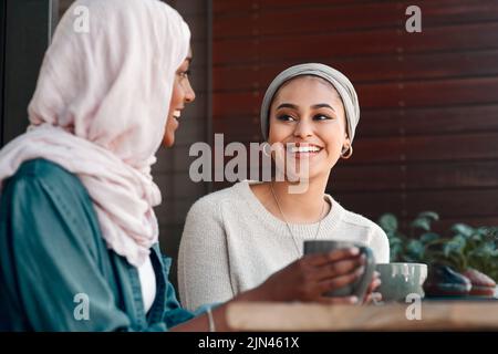 C'est vraiment très agréable de vous rattraper. Deux jeunes amies affectueuses qui ont une conversation dans un café tout en étant vêtues de hijab. Banque D'Images