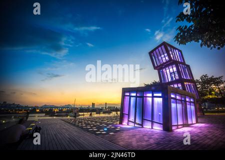 Tour d'architecture abstraite artistique à Kwun Tong Promenade, un parc urbain au bord de l'eau, à travers la ligne d'horizon et le paysage nocturne au coucher du soleil Banque D'Images