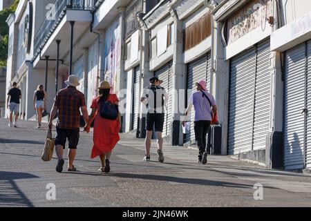 Les touristes marchent à côté de volets, hors des magasins d'affaires dans une ville côtière anglaise en bord de mer à Essex, Angleterre Banque D'Images