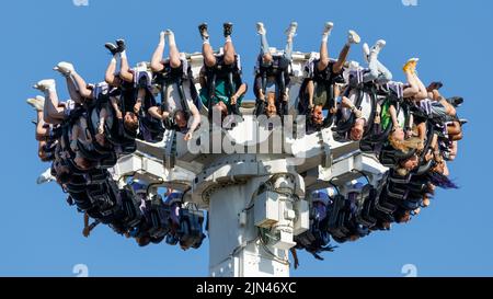 Les gens à l'envers, dans les airs sur une gondole pendule dans un parc d'attractions Banque D'Images