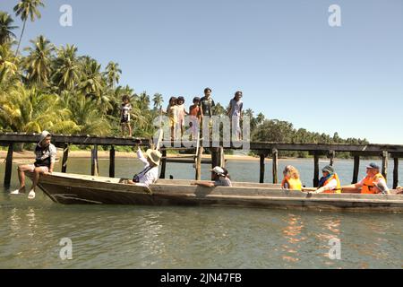 Des enfants se tenant sur une jetée comme bateau transportant des touristes arrivent au village de Horale à Seram Utara Barat, Maluku Tengah, Maluku, Indonésie. Banque D'Images