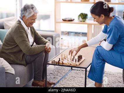 Jouer à des jeux est un excellent moyen de garder l'esprit actif. Une jeune infirmière jouant aux échecs avec une femme âgée dans une maison de retraite. Banque D'Images