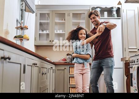 Vous prenez soin de votre père avec vos grands mouvements. Un homme et sa jeune fille dansant dans la cuisine à la maison. Banque D'Images