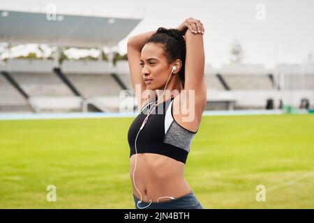 Étirez-vous avant de vous échauffer. Une jeune athlète féminine attirante s'échauffe sur la piste. Banque D'Images