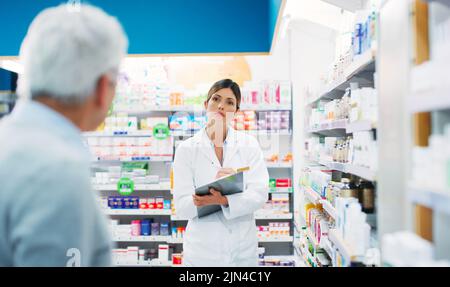 Quels symptômes avez-vous? Un pharmacien aidant un client dans un chimiste. Banque D'Images