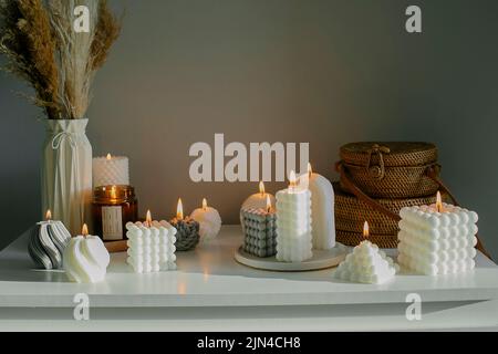 Décoration intérieure. Commode blanche avec fleurs séchées dans un vase, sacs en rotin et bougies. Encore la vie, concept d'hygge Banque D'Images