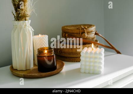 Décoration élégante avec bougie en bois et mèche dans un pot en verre brun et deux bougies. Banque D'Images