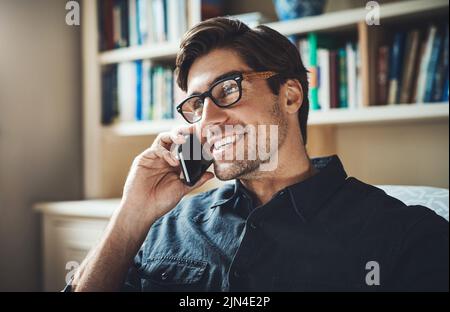 Entendre quelques bonnes nouvelles pour un changement. Un beau jeune homme d'affaires qui fait un appel téléphonique dans son bureau à la maison. Banque D'Images