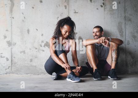 Levez-vous et partez. Photo en longueur d'un jeune couple sportif assis et reposant contre un mur. Banque D'Images
