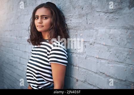 Restez authentiquement fidèle à qui vous êtes. Portrait d'une jeune femme debout contre un mur gris. Banque D'Images