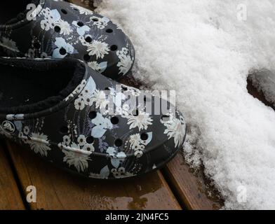 Duvall, WA, Etats-Unis - 13 janvier 2010 : paire de crocs imprimés doublés sur une terrasse en bois recouverte de neige Banque D'Images