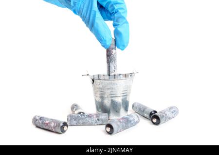 Placer les batteries usagées dans un petit seau en acier, en gros plan. Banque D'Images