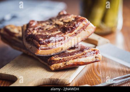 Bacon fumé entier sur une planche à découper. Banque D'Images