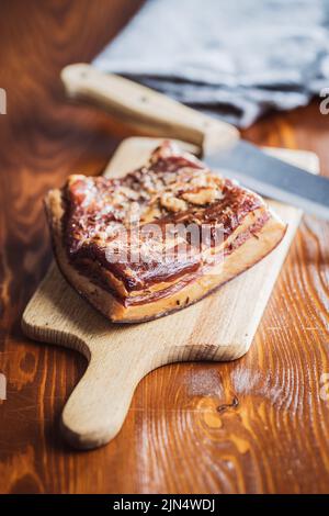 Bacon fumé entier sur une planche à découper. Banque D'Images