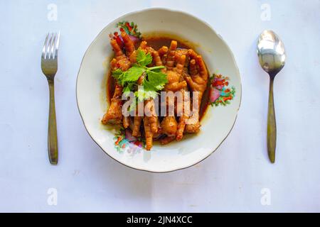 Pieds de poulet épicés au céleri, au piment, à l'oignon et à l'ail servis avec une assiette blanche sur la table Banque D'Images