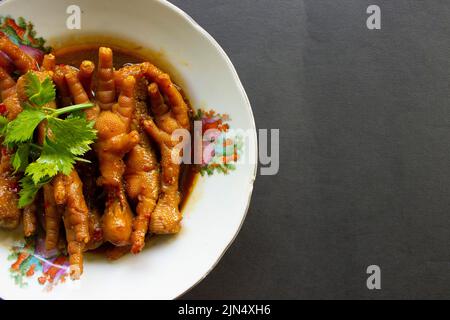 Pieds de poulet épicés au céleri, au piment, à l'oignon et à l'ail servis avec une assiette blanche sur la table Banque D'Images